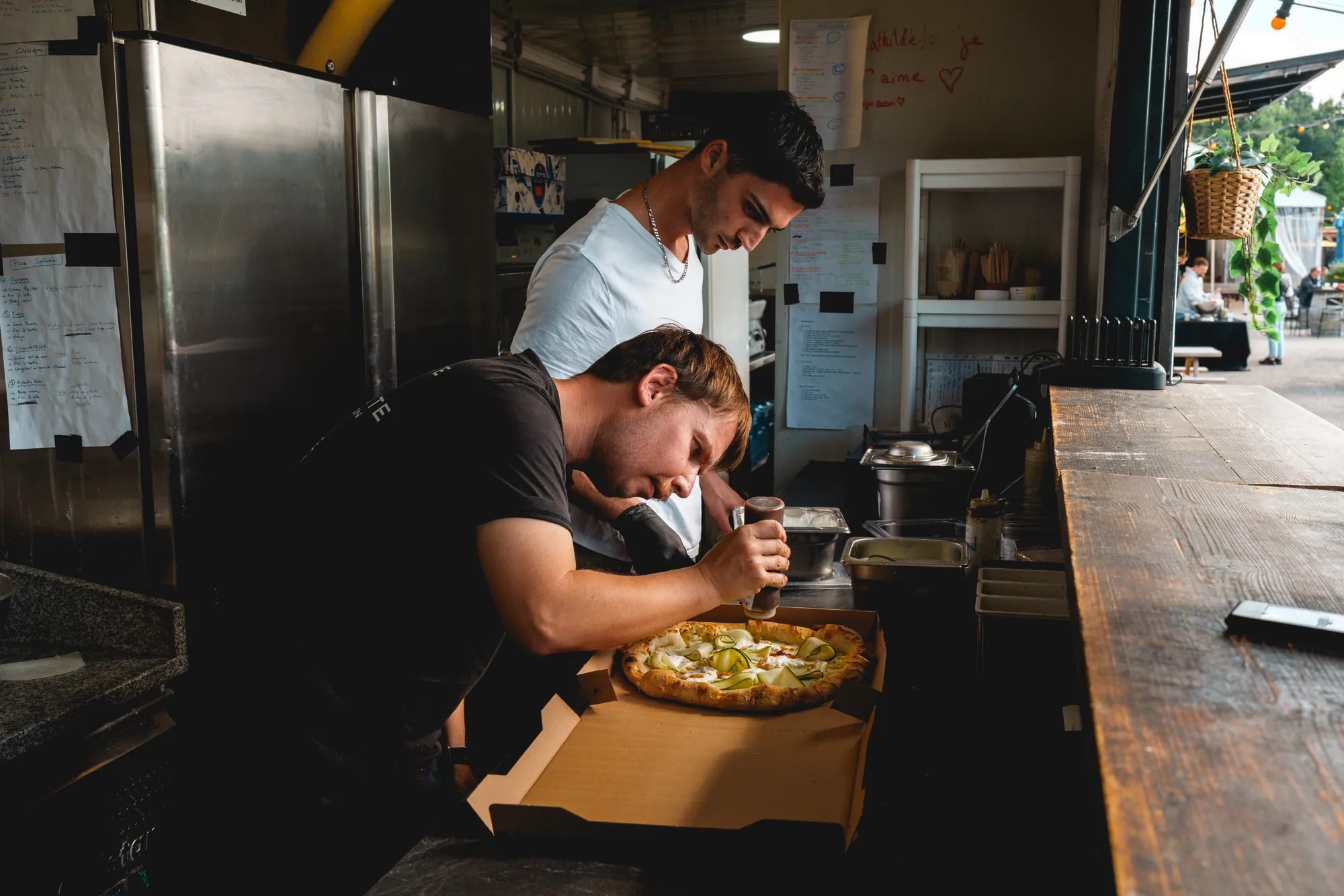 Un cuisinier surveille une pizza dans le four du food-truck