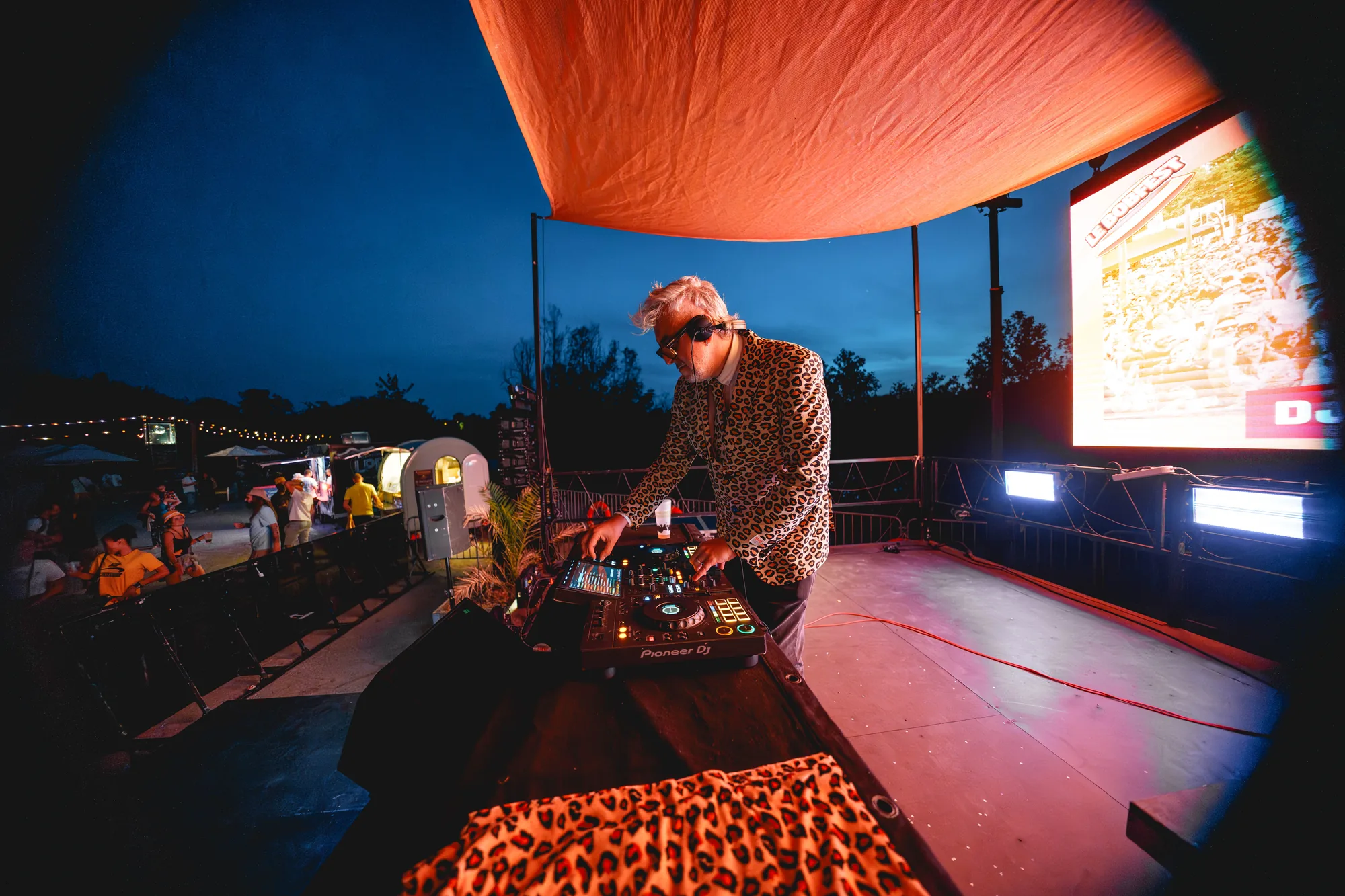 Un DJ aux platines dans les lumières bleues et orange de la nuit