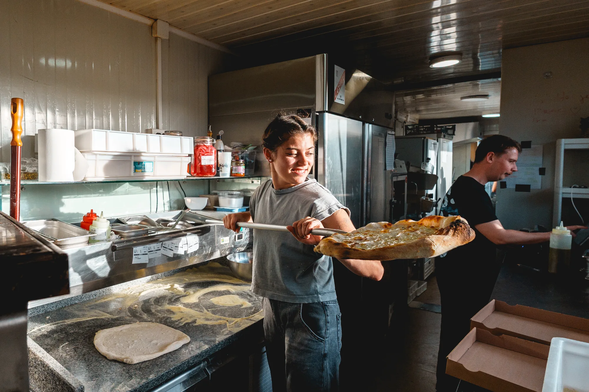 Une pizzaïola enfourne une pizza