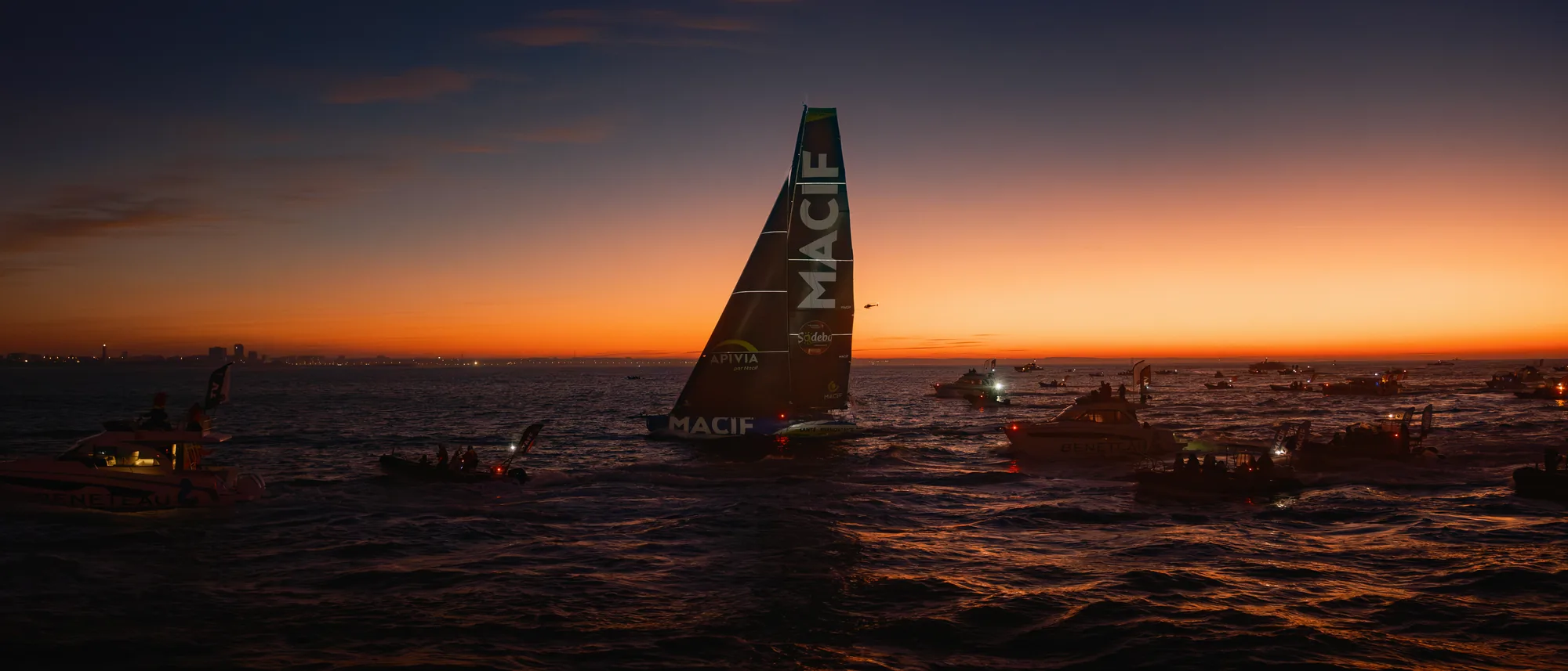L'IMOCA Macif Santé Prévoyance à l'aube, entouré de la flottille, arrivée du Vendée Globe 2024