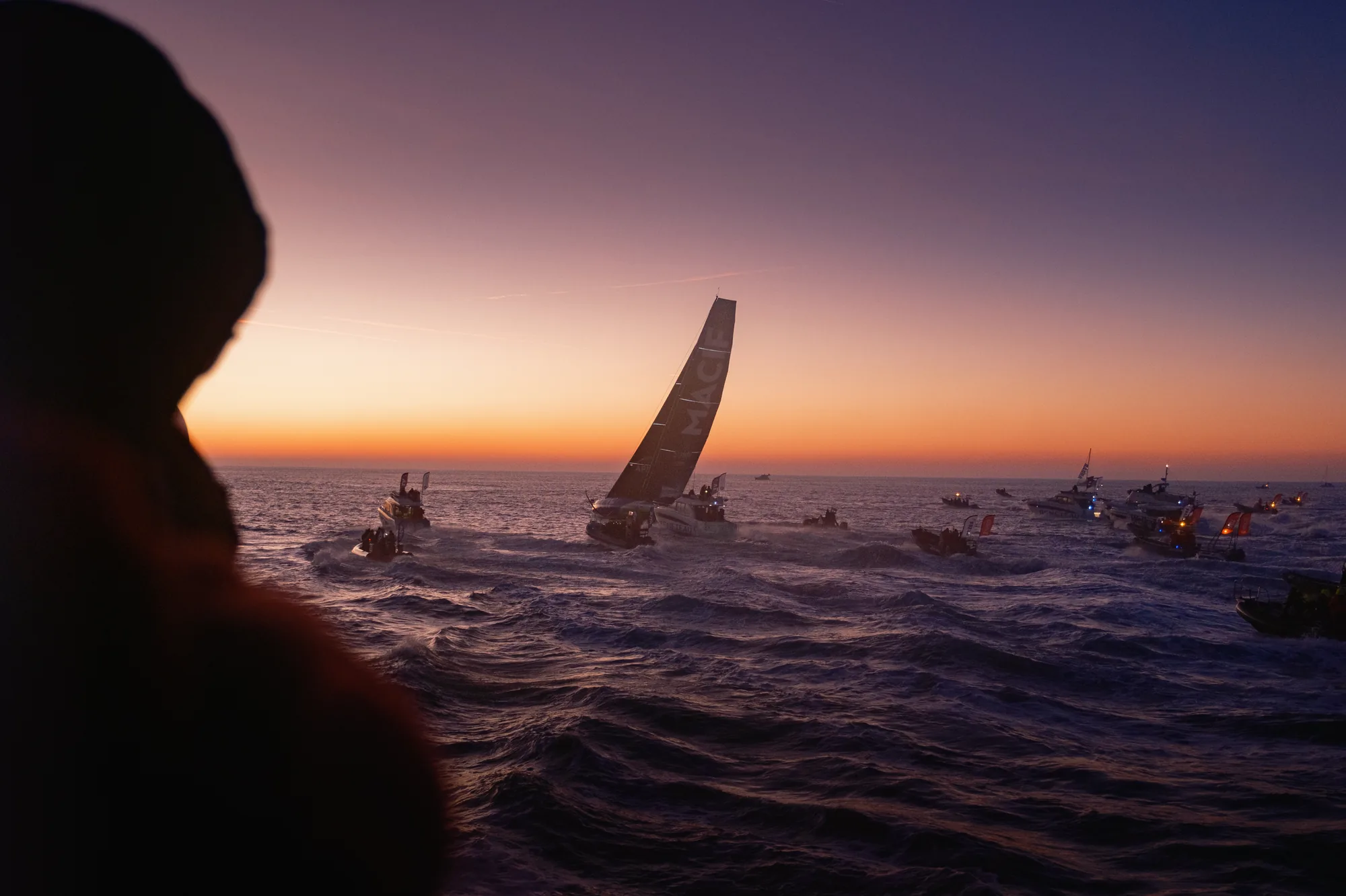 Silhouette d'un spectateur face à l'IMOCA Macif à l'aube